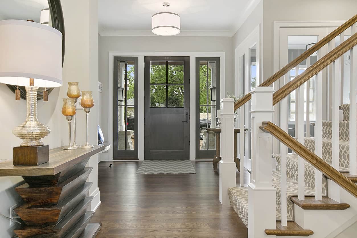 Modern Foyer with Dark Entry Door Bright residential foyer with white painted walls, dark gray entry door with sidelights, wooden staircase with white