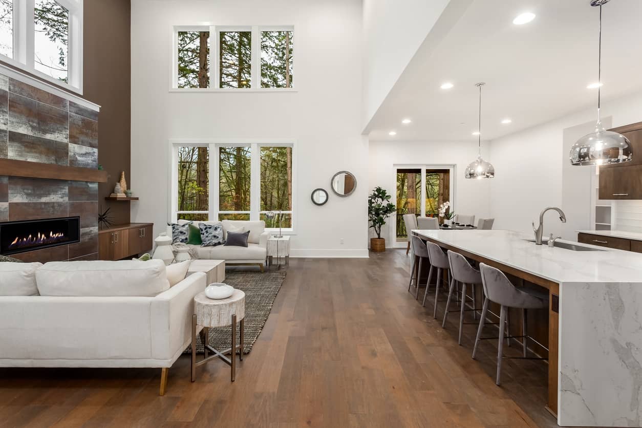 Open Concept Living Room Interior Bright open-concept interior residential space with white walls, wood flooring, and modern kitchen island with white quartz