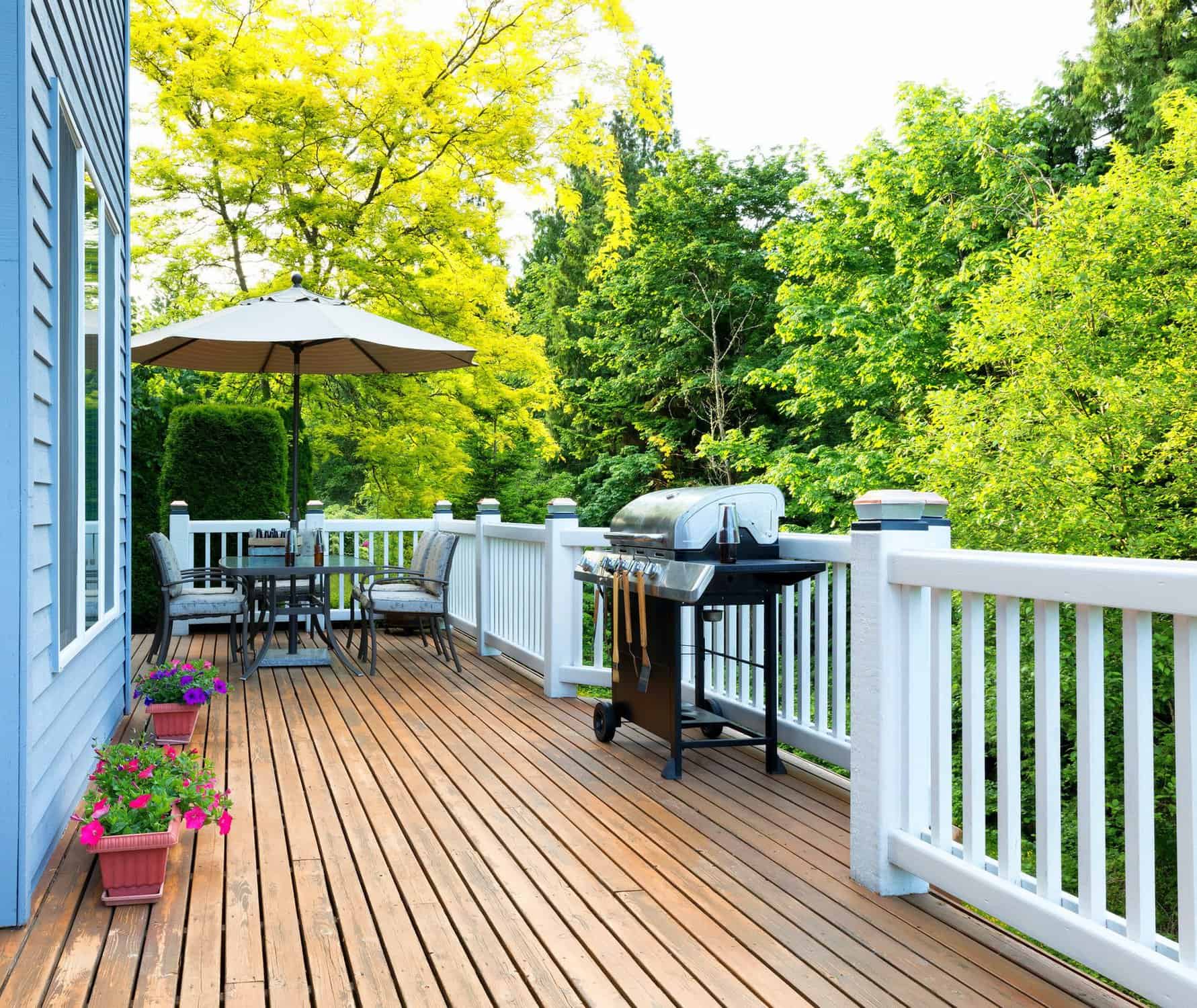 Warm Cedar Deck With White Railings Warm cedar-toned residential deck with white vinyl railings, dining furniture, grill, and potted flowers.