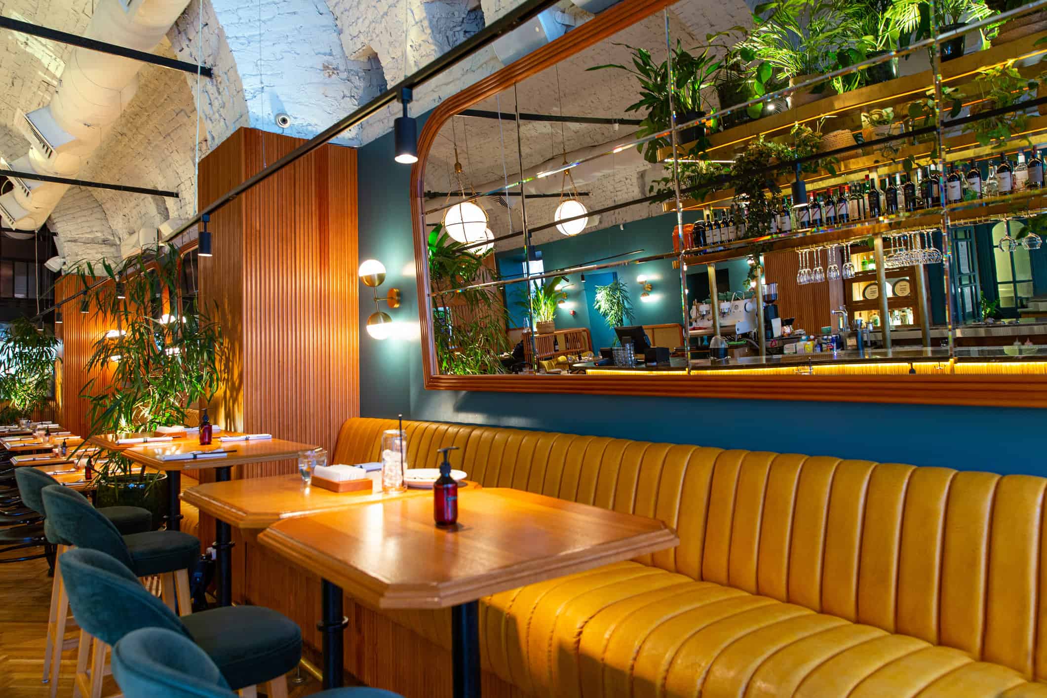 Interior commercial restaurant with teal blue painted walls, golden yellow upholstered booth seating, and wood accent