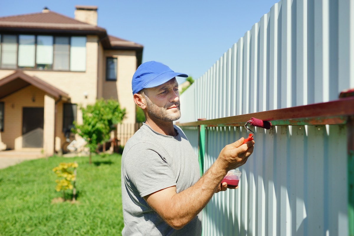 Worker painting fence. Repair home.