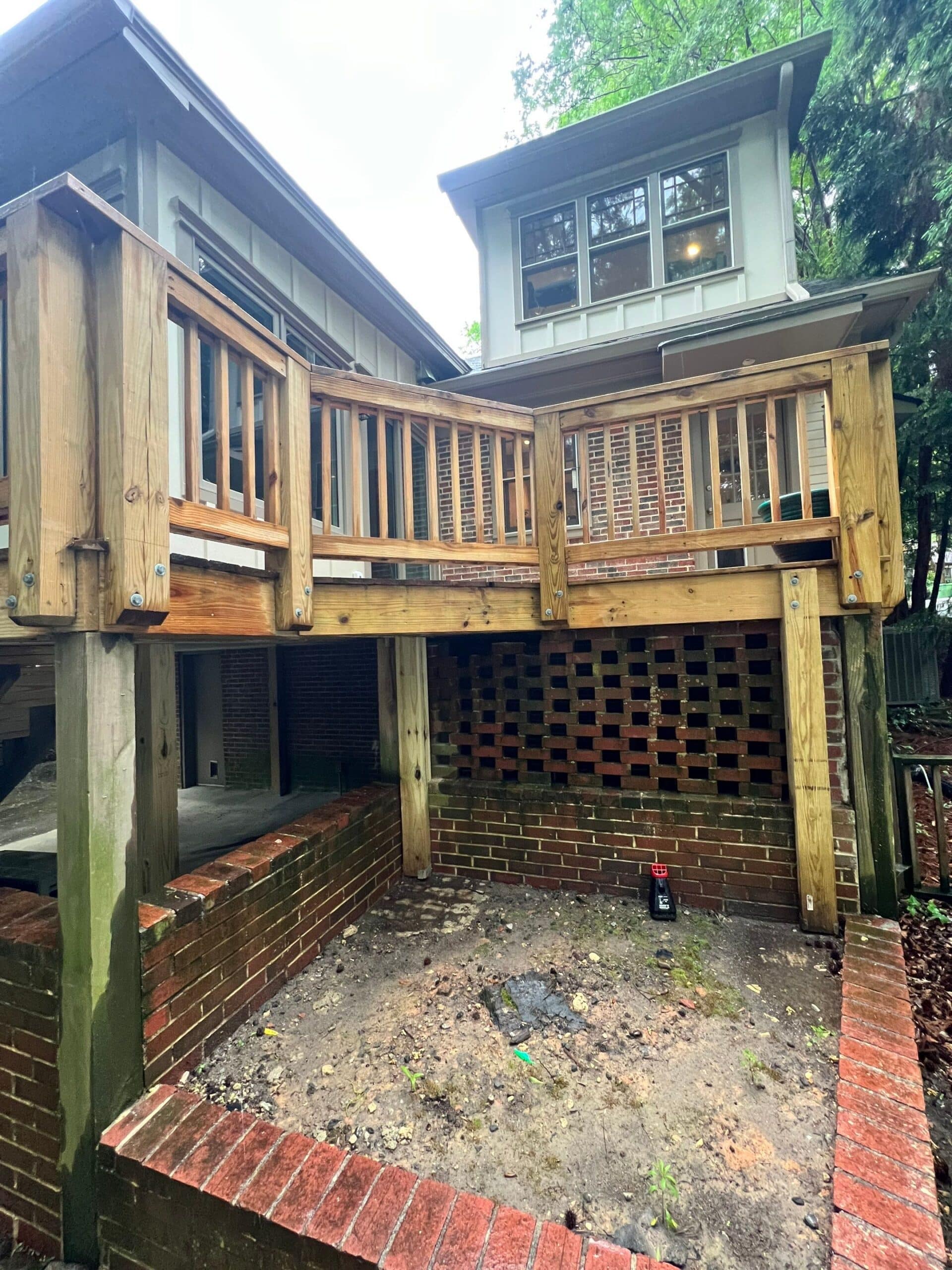 Wood Deck With Vertical Railings Golden-brown stained wood deck with vertical railings and brick foundation, attached to residential home in Atlanta, GA.